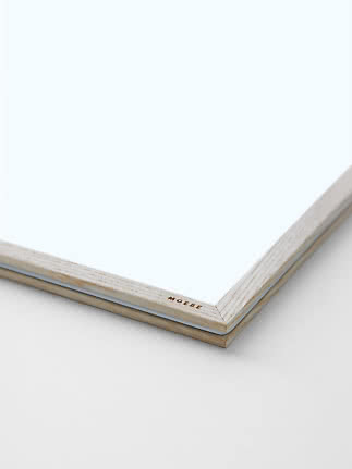 Close-up of a light wood frame with white insert and MOEBE logo on the corner