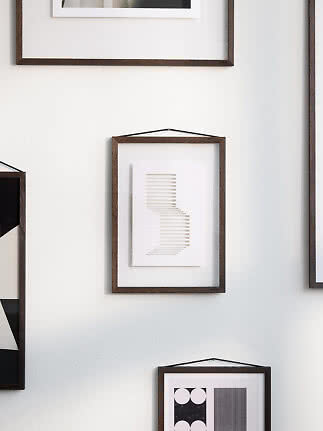 Dark wood frame with abstract beige line print hanging on a white wall