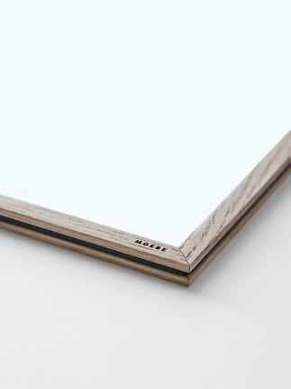 Close-up of a light wood frame with clear glass and MOEBE logo in the corner