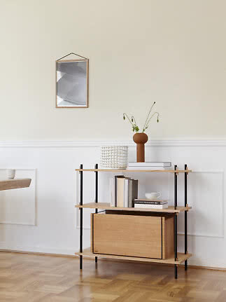 Light wood shelving unit with black legs, vase with flowers and books in a minimalist room