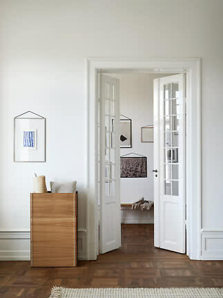 Wooden cabinet with cushion and roll by a white wall and open French doors