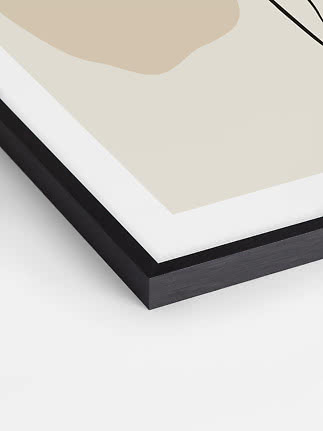 Close-up of framed abstract print with beige shapes, white border, and black frame