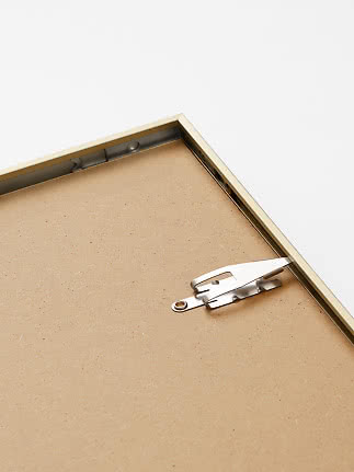 Close-up of the back of a gold-colored picture frame with metal hanger