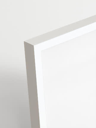 Close-up of the corner of a white picture frame with a wide border