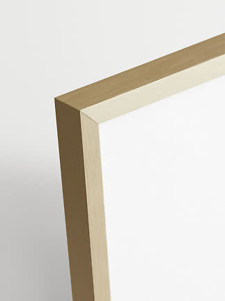 Close-up of a brushed gold metal frame corner against a white background