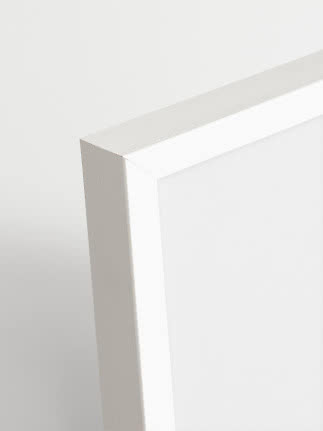 Nahaufnahme einer weißen Holzbilderrahmen-Ecke mit glattem, schlichtem Profil