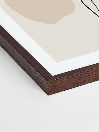 Nahaufnahme eines dunklen Holzrahmens mit weißem Passepartout um einen abstrakten Kunstdruck.