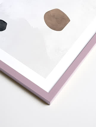 Primo piano in diagonale dell’angolo di una cornice quadrata in viola pastello, con passepartout bianco e una stampa astratta sotto vetro