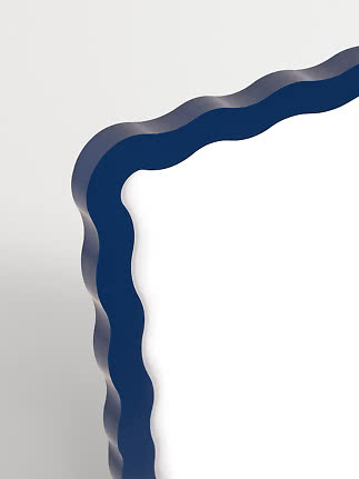 Nahaufnahme eines wellenförmigen Spiegels mit blauem Rahmen vor hellem Hintergrund