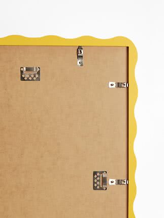 Back of yellow picture frame with wavy edge and metal hanging hardware