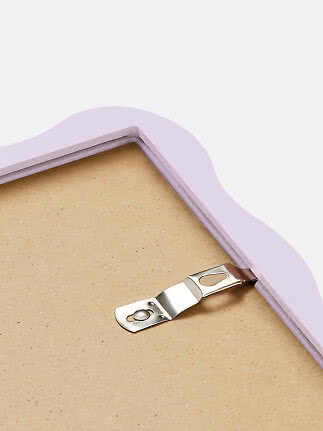 Back of a wavy light pink picture frame with metal hanging hook