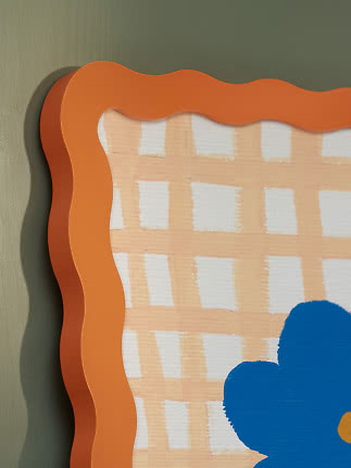 Close-up of wall art with wavy orange frame, check pattern and blue flower