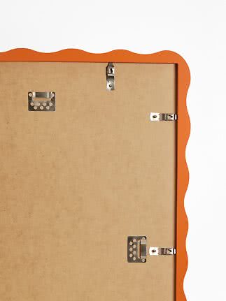 Back of orange frame with wavy edge and metal wall hanging hardware