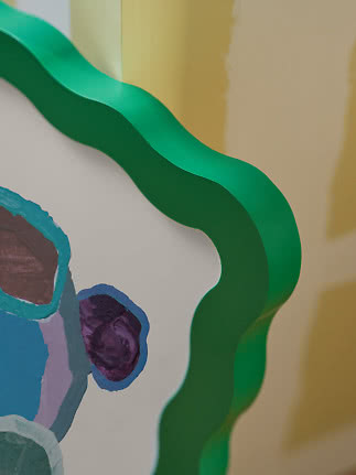 Close-up of abstract artwork with green wavy edge and colorful painted shapes