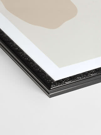 Close-up of black picture frame with ornate detailing and white mat board