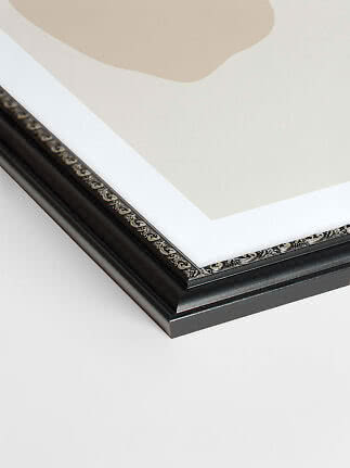 Close-up of black picture frame with silver detailing at the corner and white mat