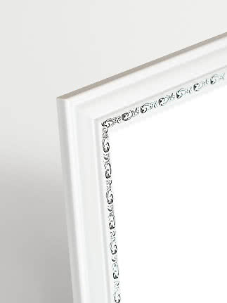 Close-up of white picture frame with silver details and decorative inner edge