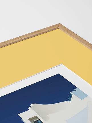 Primo piano in diagonale dello smusso di un passepartout in giallo dentro una cornice in rovere, con un poster blu sotto vetro