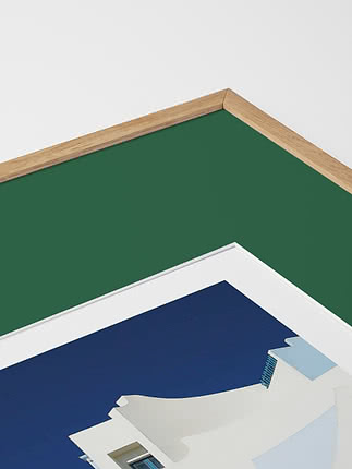 Primo piano in diagonale dello smusso di un passepartout in verde dentro una cornice in rovere, con un poster blu sotto vetro