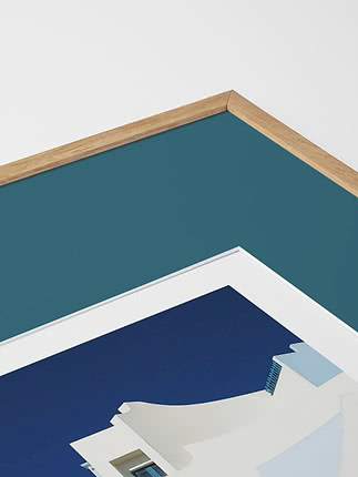 Primo piano in diagonale dello smusso di un passepartout in verde acqua dentro una cornice in rovere, con un poster blu sotto vetro