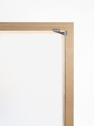 Bagside af træramme med hvid plade og savtakket ophæng i øverste hjørne
