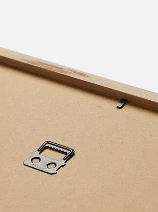 Close-up of the back of a wooden frame with a metal hanging bracket.
