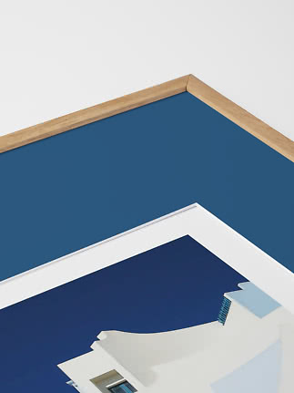 Close-up of framed print with blue background and white building in a wooden frame