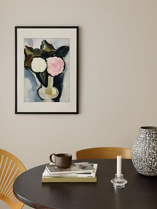 Framed floral print in a black frame above a table with books, mug, candleholder and large vase