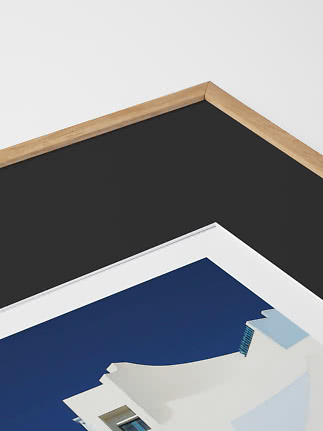 Close-up of framed print with black mat and light wood frame.