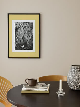 Framed black-and-white forest illustration with yellow mat above a round dining table