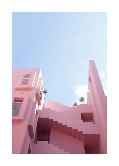 Rosa byggnad med geometriska trappor mot blå himmel och små palmer