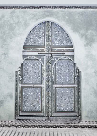 Ornate double door with geometric patterns set in a white arched wall