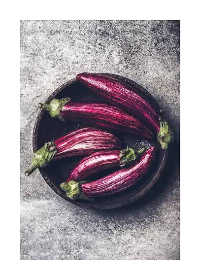 Bol d’aubergines longues violettes rayées sur une surface en pierre grise