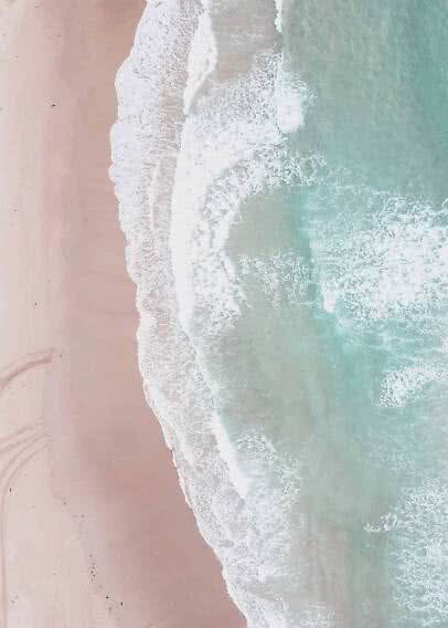 Aerial view of waves washing onto a pale sandy beach