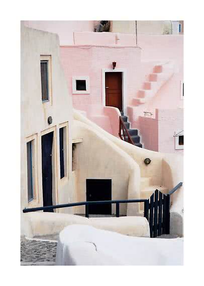 Pastel-colored houses with curved walls, stairs, and dark doors along a narrow alley