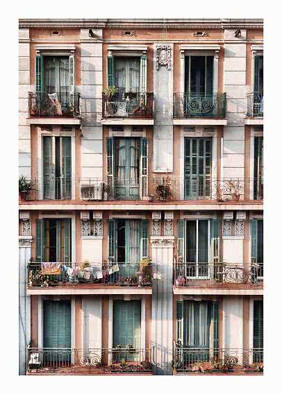 Fachada de edificio con persianas verdes, balcones de hierro forjado y plantas