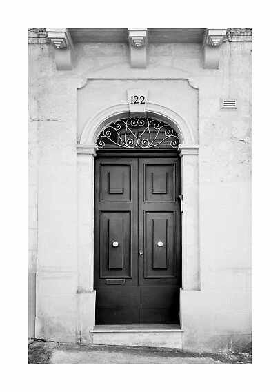 Black double door in arched stone doorway with wrought iron detail and house number 122