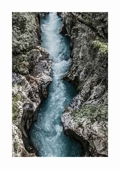 Fiume turchese che scorre in una stretta gola rocciosa tra pietre e vegetazione