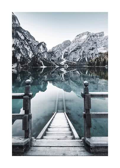 Wooden steps leading into a calm mountain lake with reflections of pale cliffs and forest