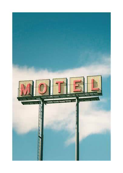 Vintage motelskilt på høje stolper mod blå himmel med skyer