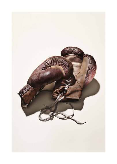 Guantoni da boxe vintage usurati in pelle marrone con lacci su sfondo chiaro