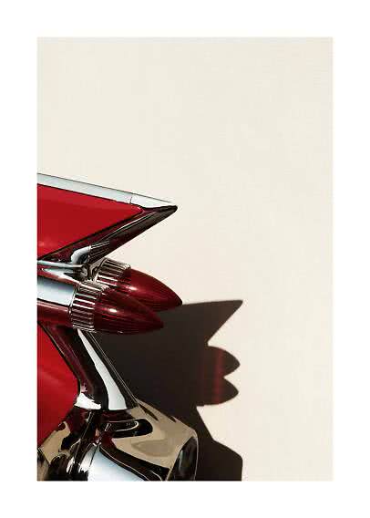 Close-up of a red vintage car tail fin with chrome and double tail lights against a light wall