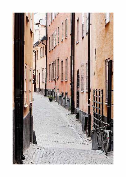 Narrow cobblestone street between pastel buildings with a bicycle parked on the right