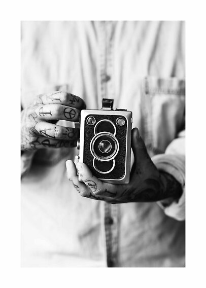 Mani tatuate tengono una fotocamera vintage in un primo piano in bianco e nero