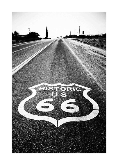 Sort-hvidt foto af en øde vej med Historic US 66-maleri på asfalten