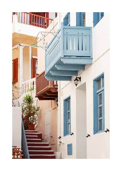 Narrow alley with white houses, blue balconies and windows, red steps, and potted plants