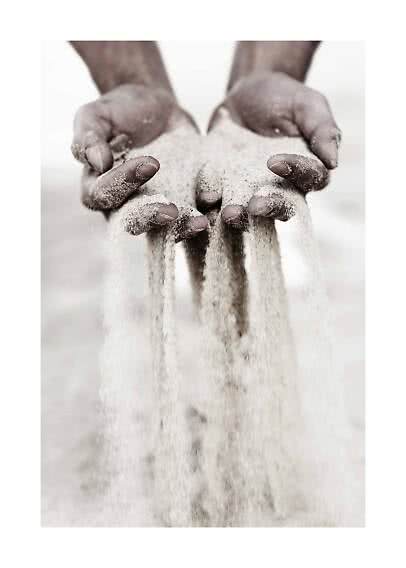 Hands holding fine sand as it pours down between the fingers
