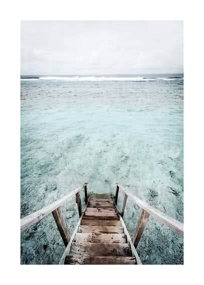 Holztreppe ins klare türkisfarbene Meer unter bewölktem Himmel