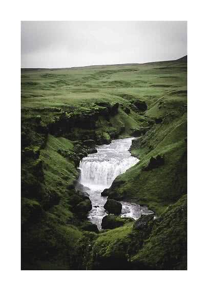 Small waterfall in a mossy green canyon under an overcast sky
