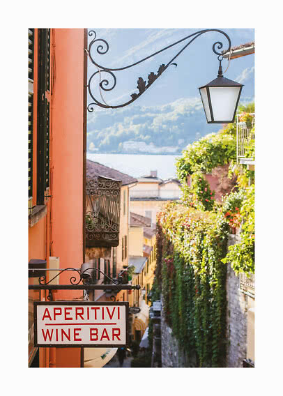 "Aperitivi Wine Bar" sign on a sunny narrow street with hanging lantern and lake view